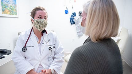 Cleveland Clinic caregiver talking to patient, both in masks