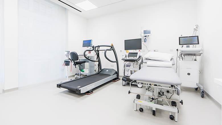 Doctor's office with a bed, monitors and a treadmill.