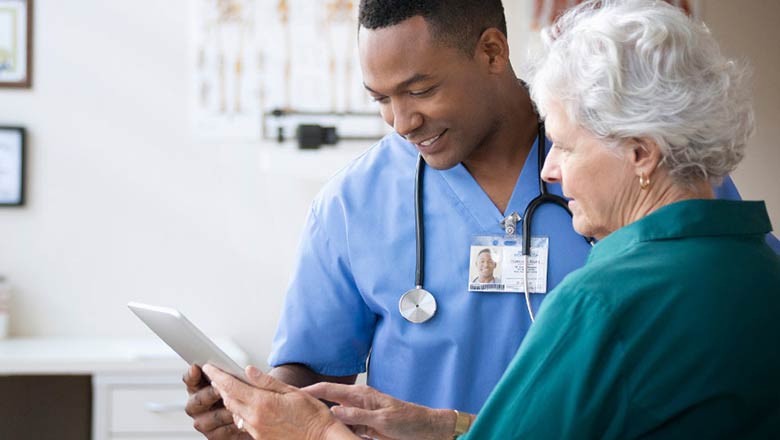 Caregiver reviewing information on a tablet with a patient.