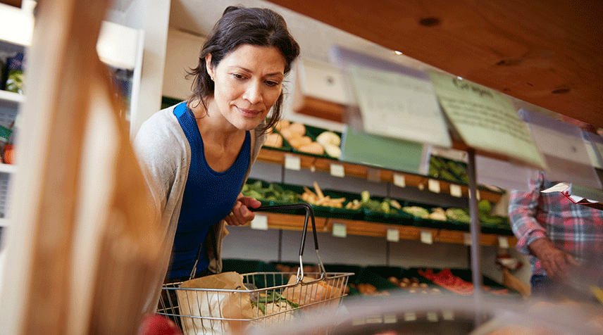 Person shopping for groceries and selecting fresh produce from a market.