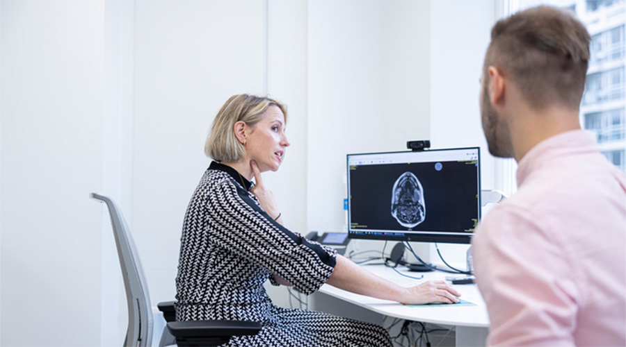A Cleveland Clinic London caregiver pointing at her throat while showing someone an X-ray of a skull