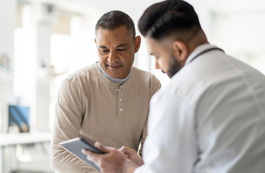 Consultant showing patient information on a digital tablet during a consultation.