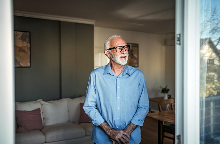 Man standing with a cane looking outward.