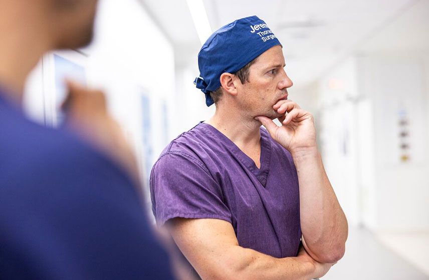 Doctor resting his hand on his chin with his arms crossed.