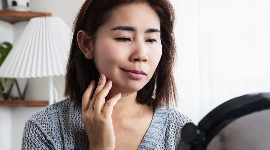 A woman with facial palsy looking at herself in a mirror.