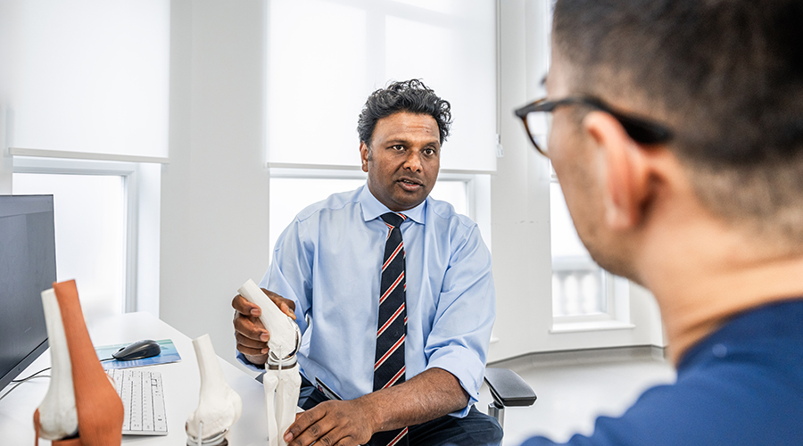 Knee specialist Sam Rajaratnam FRCS consulting with a patient