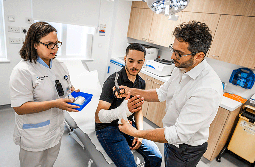 Doctor wrapping a patient's arm with a soft fabric bandage in preparation for a splint/cast.